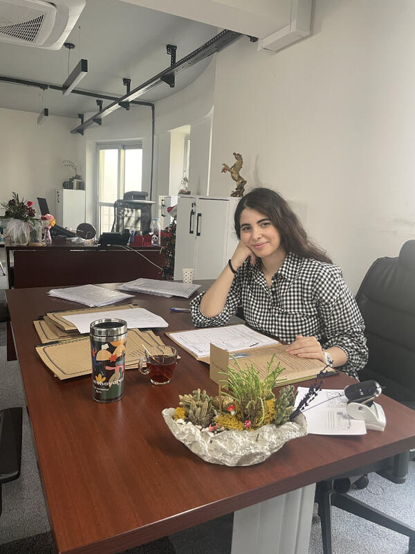 Gamzenur Erdogan at her desk with personnel files and paperwork spread across the table